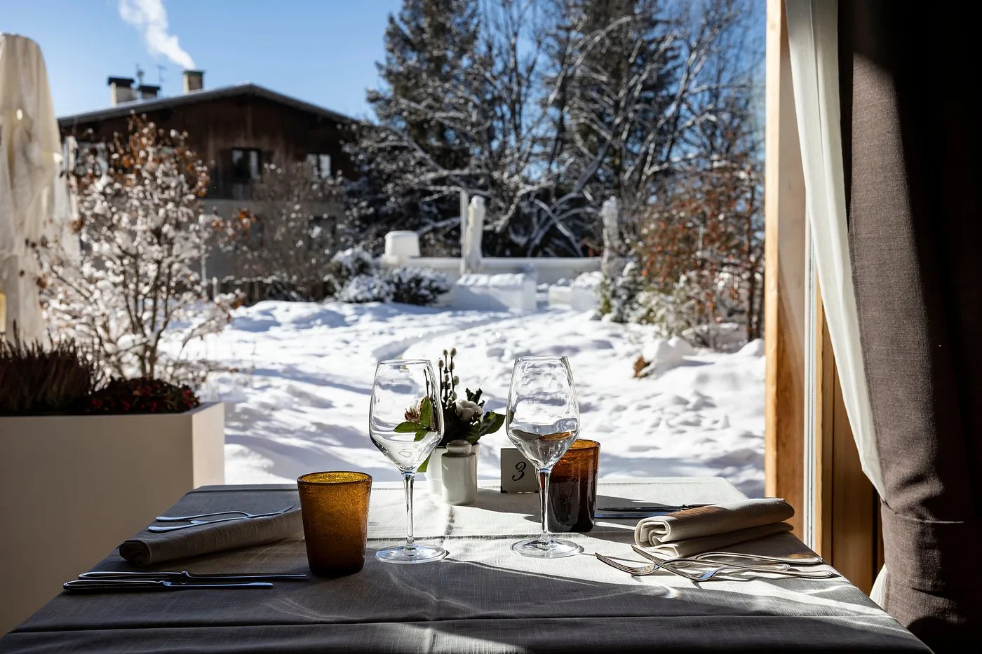 Tavolo del ristorante apparecchiato con vista sul giardino innevato