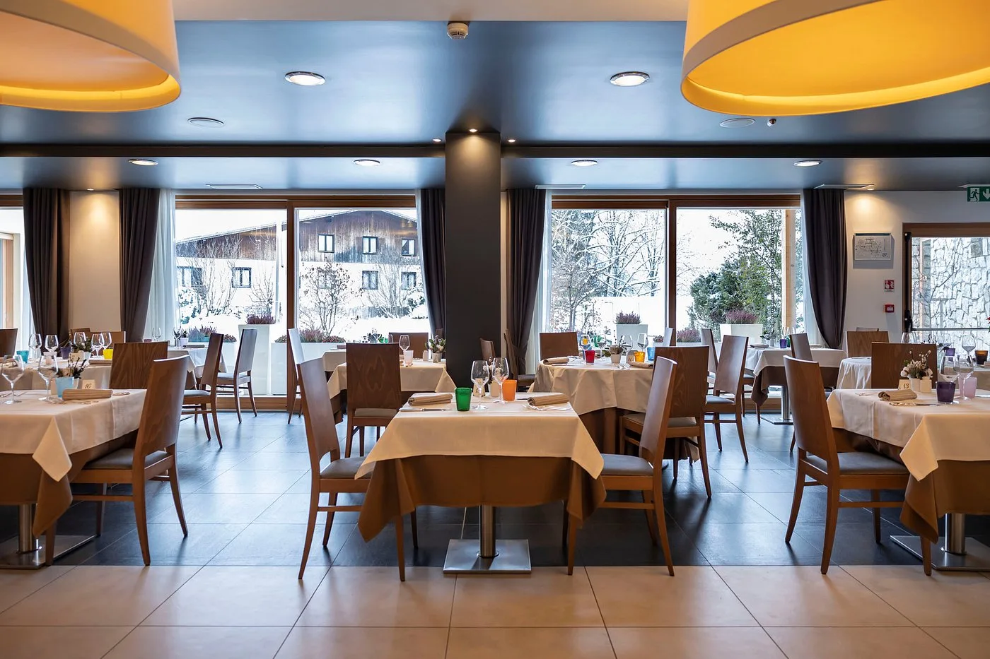Sala ristorante dell'hotel con tavoli apparecchiati e ampie vetrate sulla neve