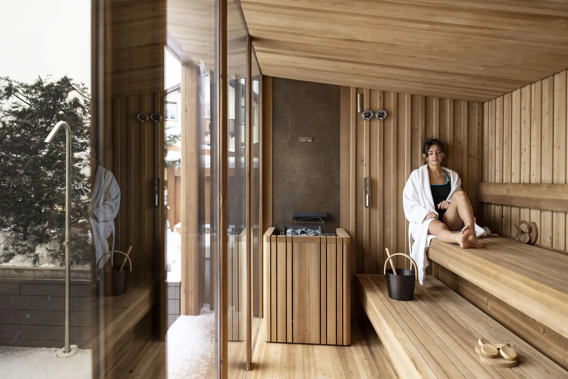 Sauna finlandese in legno con vetrata affacciata sul giardino innevato
