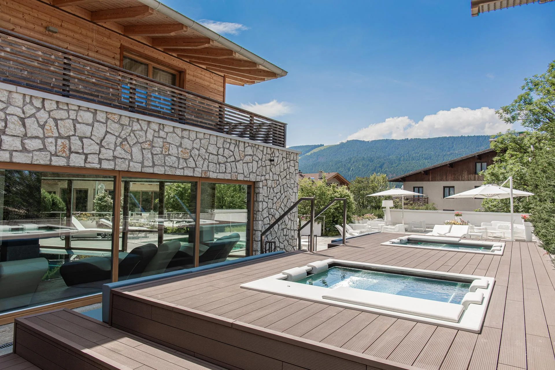 Vasche idromassaggio esterne su terrazza in legno con vista sulle montagne verdi