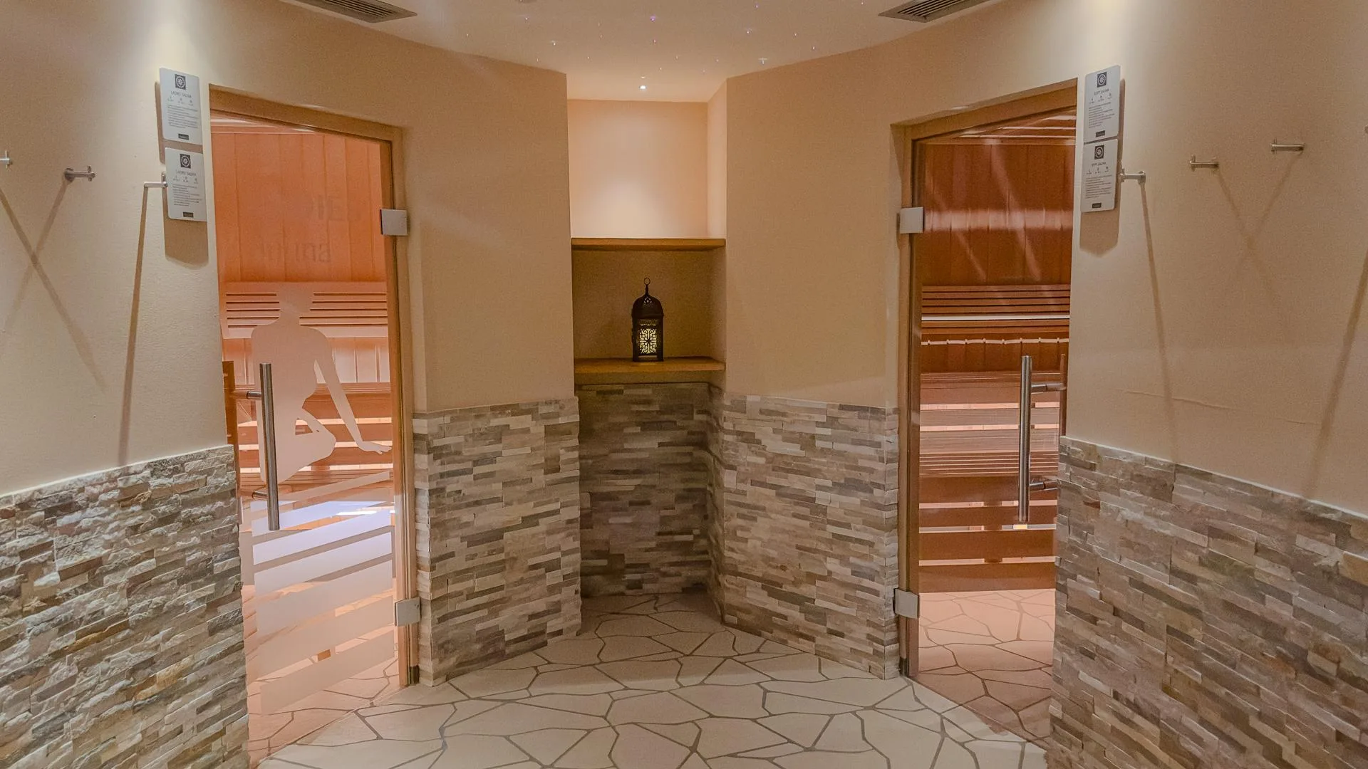 Ingresso delle saune della spa con rivestimenti in pietra e porte in vetro