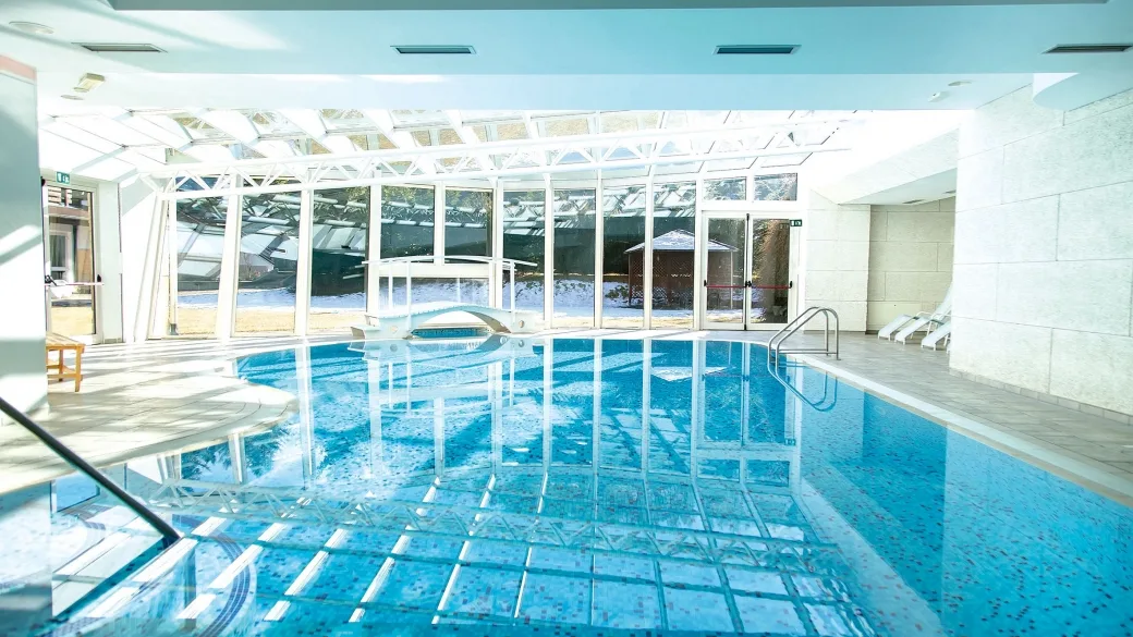 Piscina coperta con grandi vetrate affacciate sul paesaggio innevato e acqua azzurra