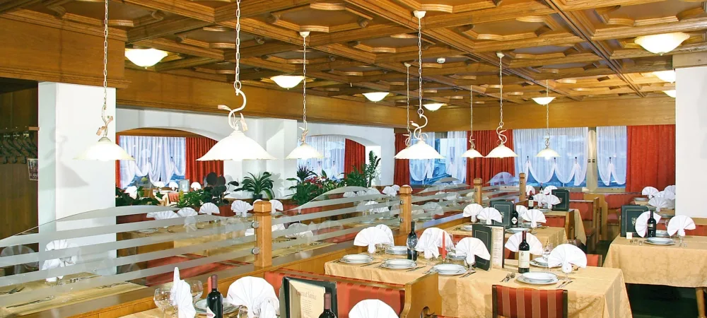 Sala ristorante elegante con tavoli apparecchiati e soffitto in legno a cassettoni