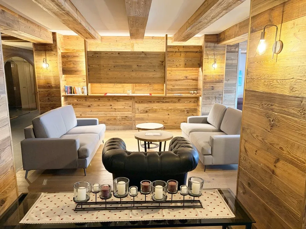 Salotto rustico con pareti in legno, divani grigi e candele decorative