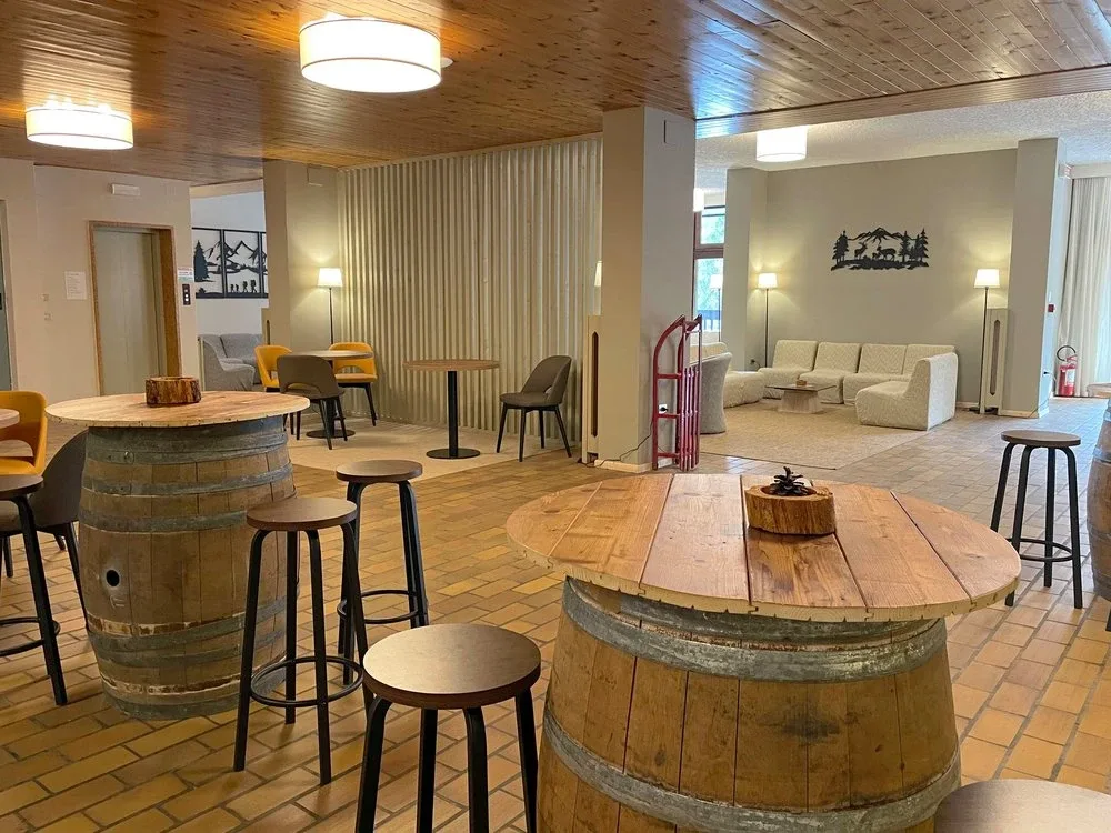 Area lounge con tavoli alti ricavati da botti in legno e divani sullo sfondo