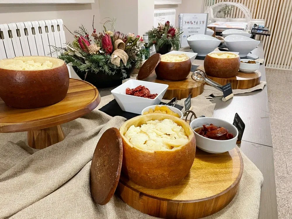 Buffet con formaggi serviti in forme di pane e composte su assi di legno