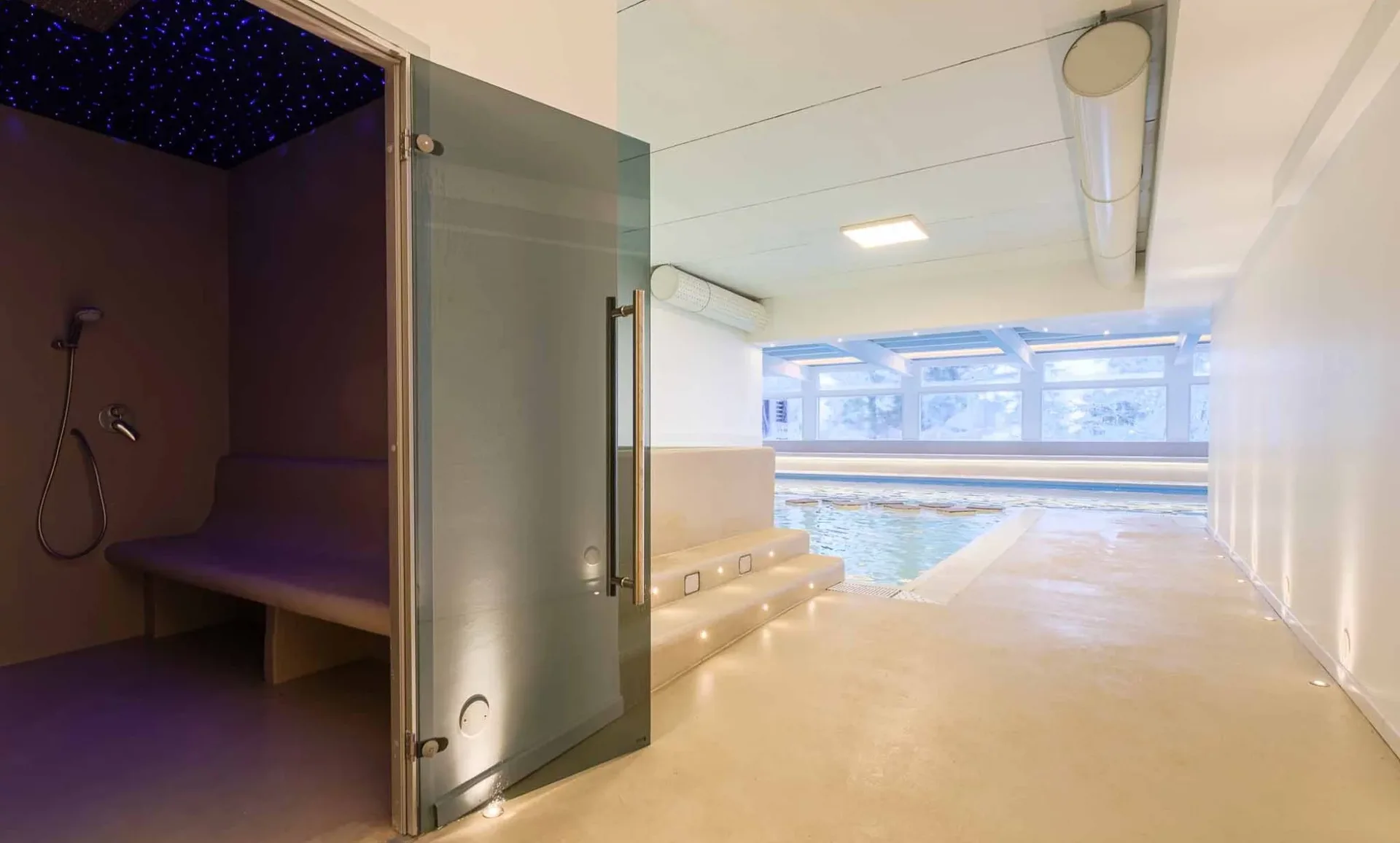 Area wellness con bagno turco e piscina coperta vista neve