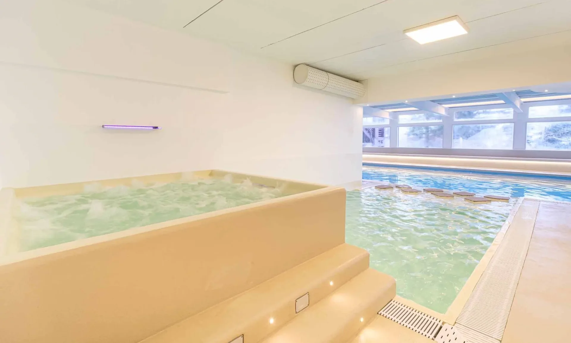 Vasca idromassaggio accanto alla piscina interna con vista sulla neve
