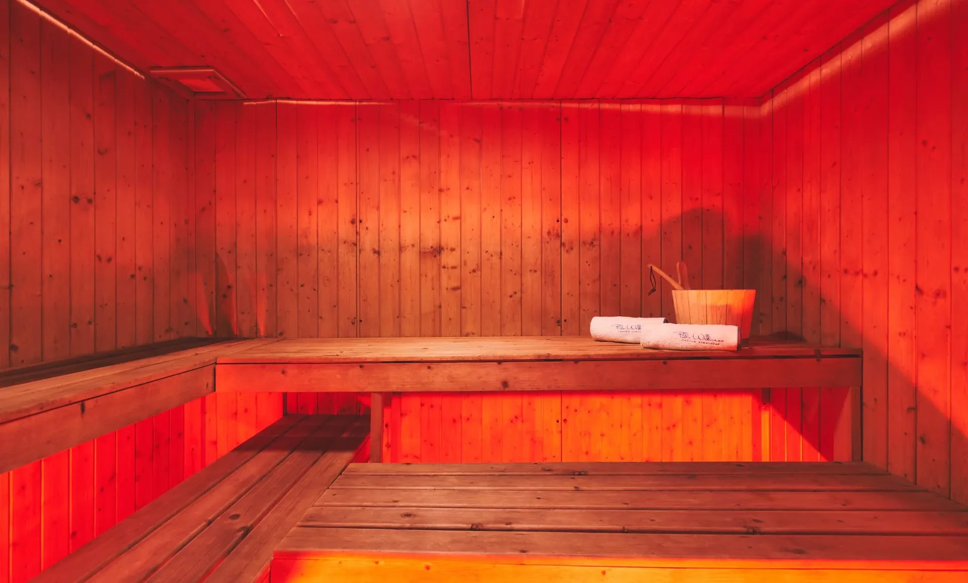 Interno di una sauna in legno con illuminazione rossa calda