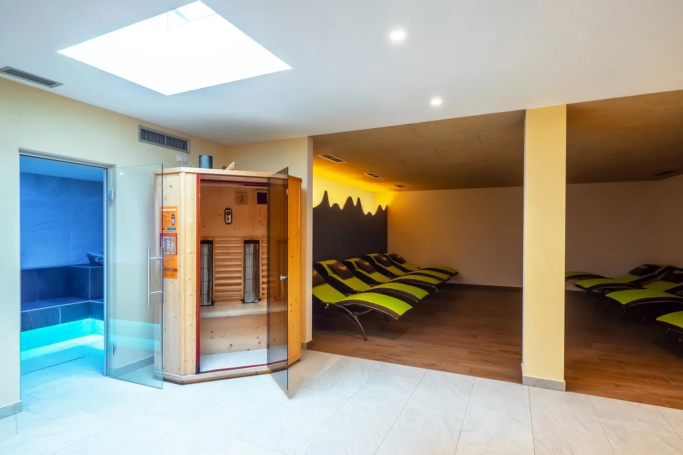 Zona relax della spa con sauna in legno, bagno turco e lettini verdi