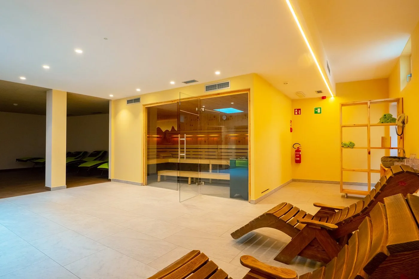Zona sauna finlandese in legno con lettini relax e pareti gialle