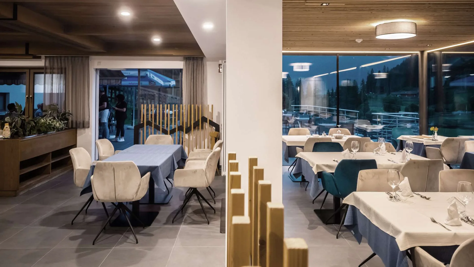 Interno del ristorante elegante con tavoli apparecchiati e vetrate serali