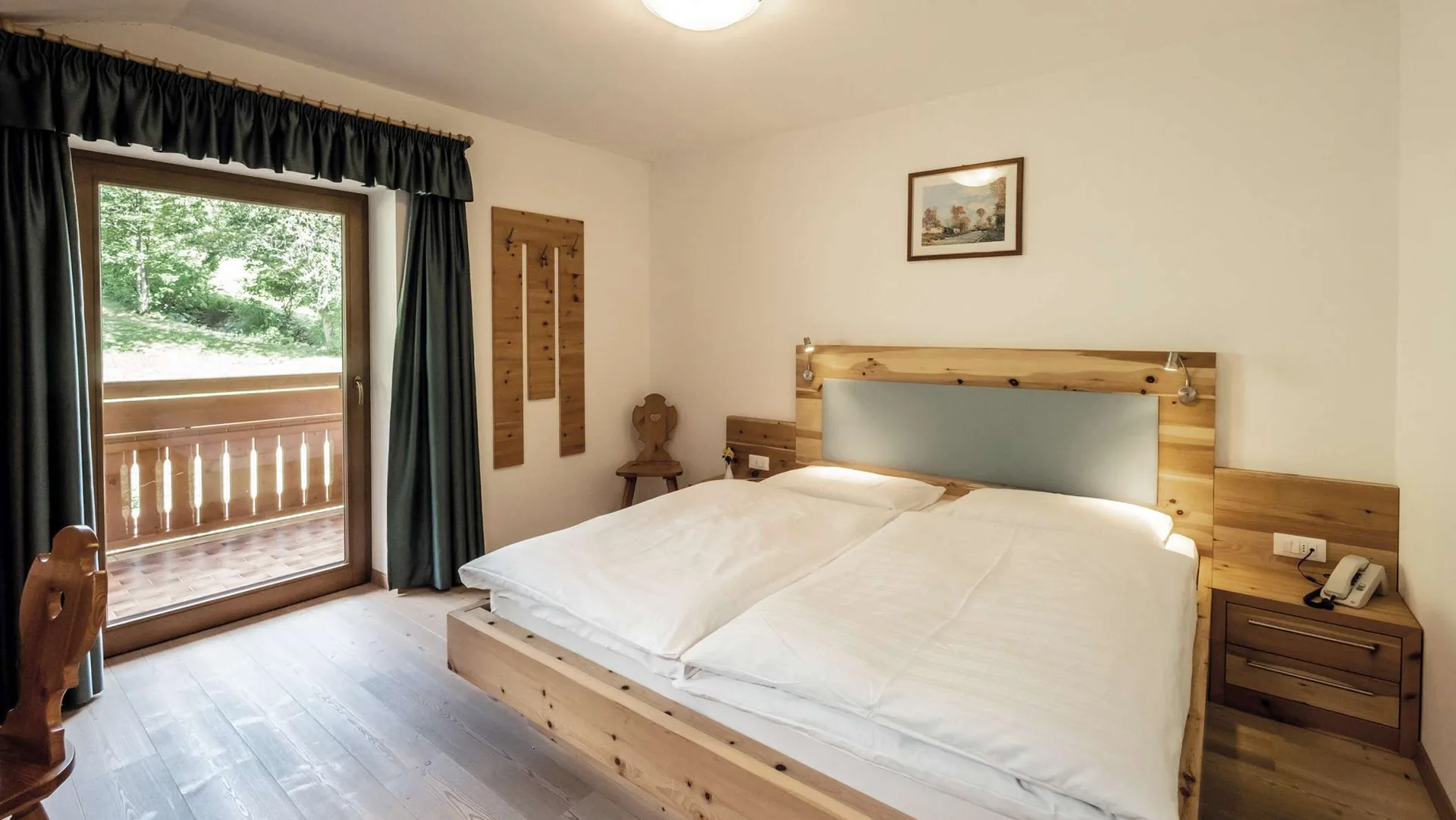 Camera doppia con letto in legno, balcone e vista sul bosco