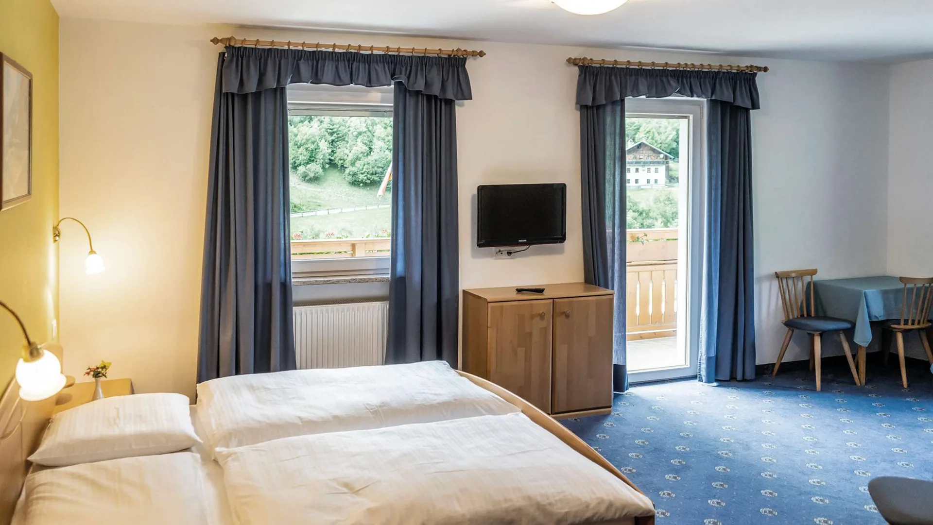 Camera doppia con letto matrimoniale, TV, tavolino e vista sul verde
