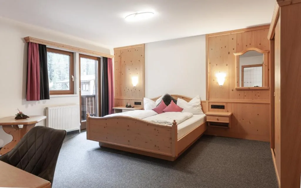 Camera da letto con rivestimenti in legno di pino, letto matrimoniale e balcone