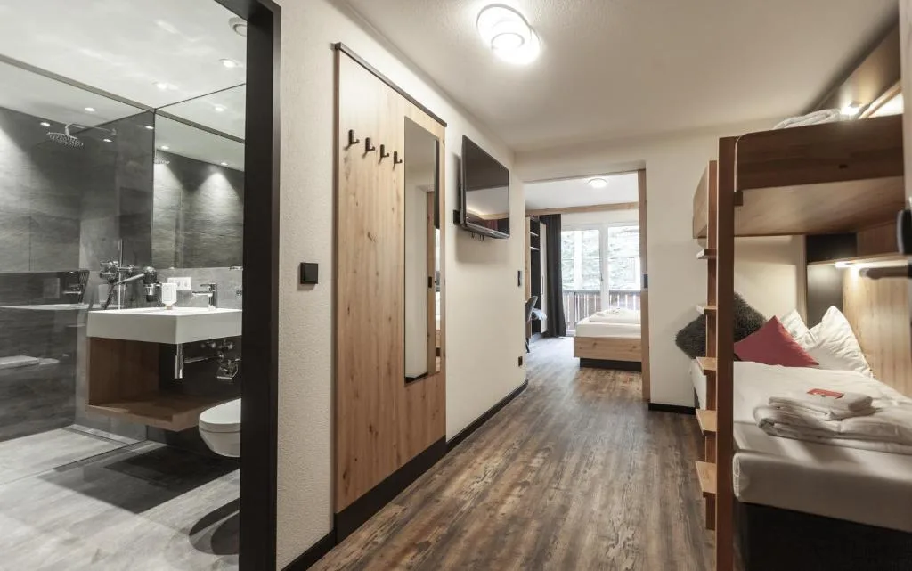 Interno di camera moderna con bagno aperto, doccia a pioggia, letto a castello e pavimento in legno