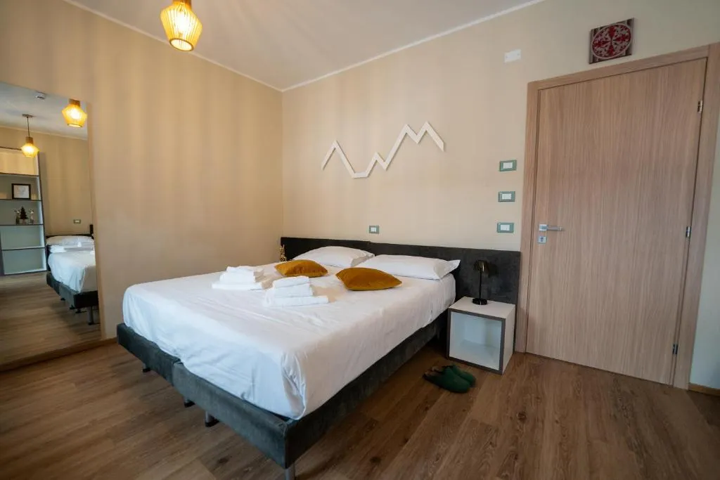 Camera matrimoniale con decorazione a profilo di montagna, parete beige e pavimento in legno