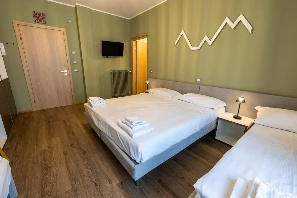 Camera tripla con letto matrimoniale e singolo, pareti verdi e TV a parete