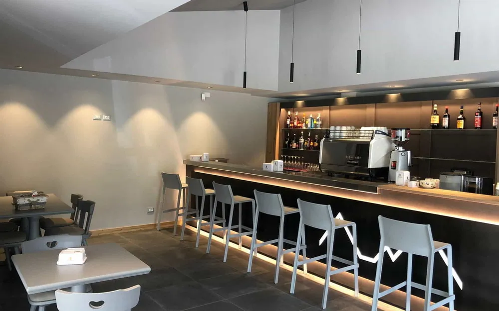 Area bar con sgabelli, macchina del caffè professionale e tavoli