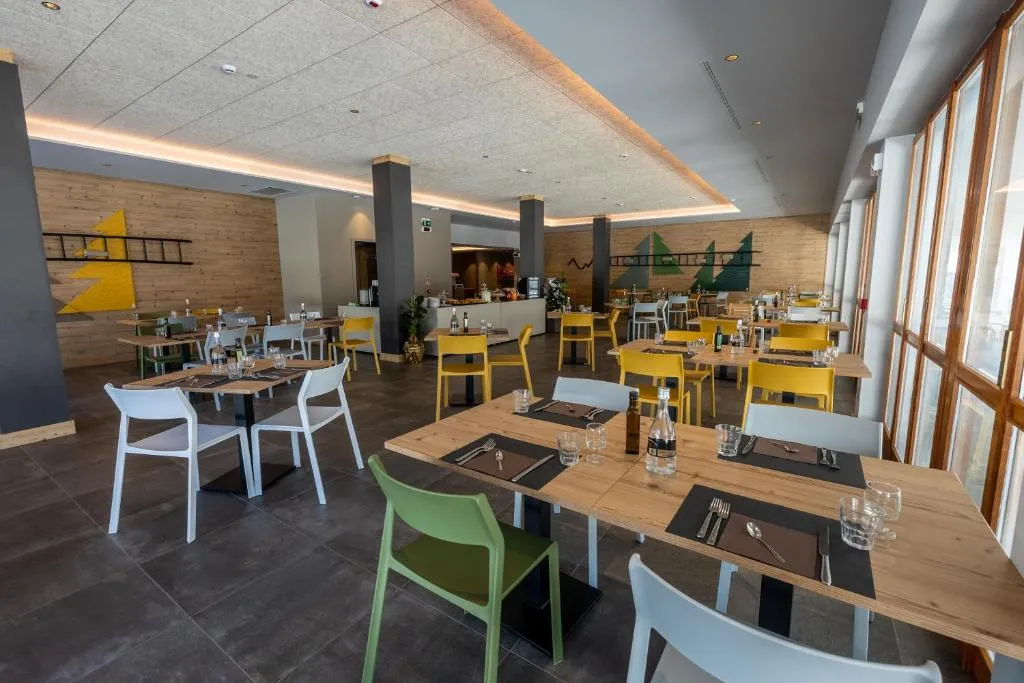 Sala ristorante moderna con tavoli in legno, sedie colorate e decorazioni a tema montano