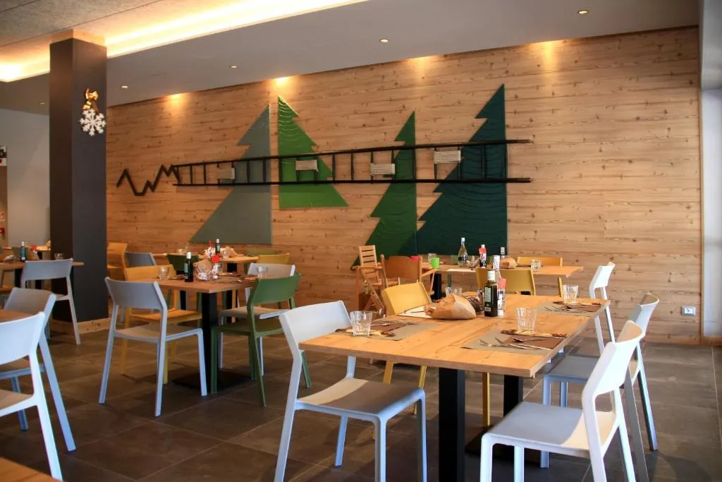 Sala ristorante con parete in legno decorata con alberi stilizzati e tavoli apparecchiati