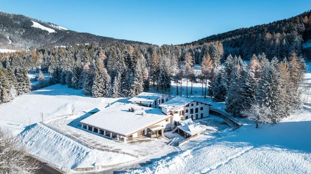 Vista panoramica invernale dell'hotel tra montagne innevate e foresta di abeti