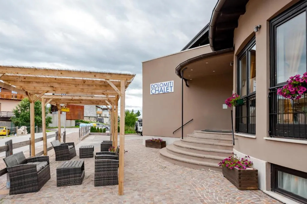 Ingresso dell'hotel Dolomiti Chalet con pergolato in legno, poltrone e area lounge esterna