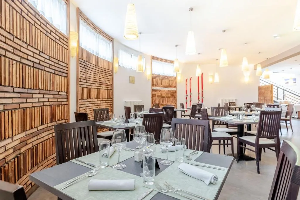 Sala ristorante luminosa con pareti in legno, tavoli apparecchiati e sci rossi decorativi