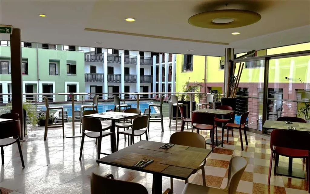 Sala ristorante con tavoli apparecchiati e ampie vetrate sulla piscina