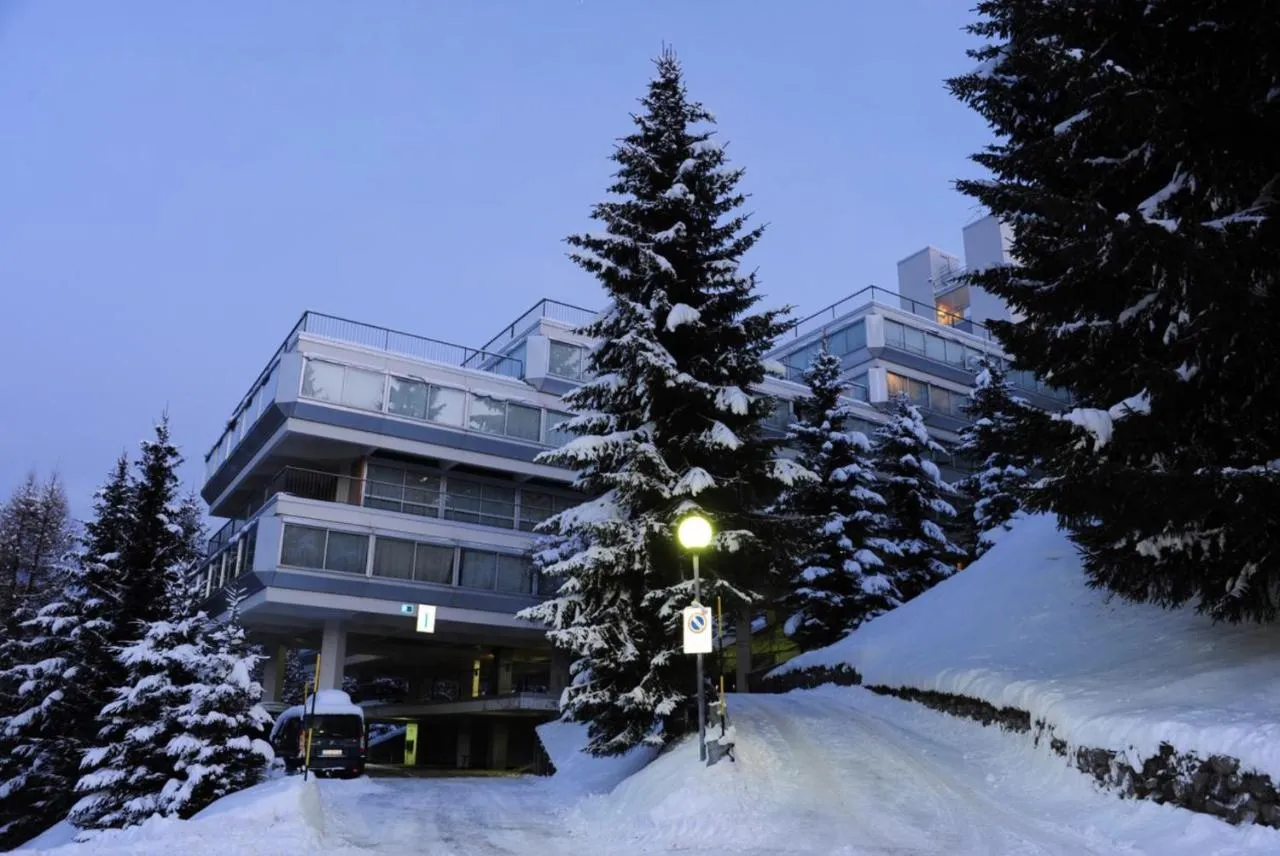 Edificio dell'hotel immerso nella neve con abeti e strada illuminata al crepuscolo